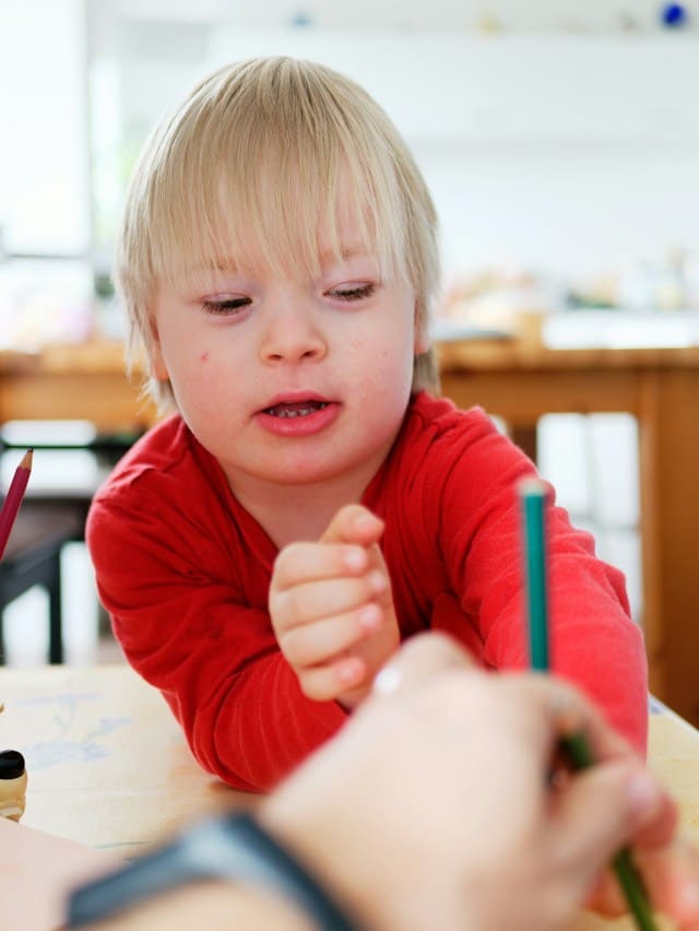 A young kid writing with a pencil